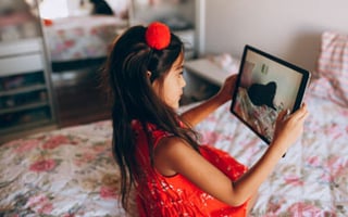 A small child on a bed with a tablet