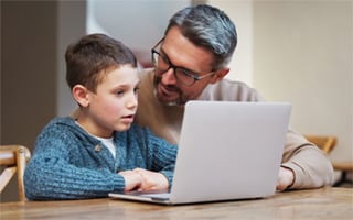 A parent with a child at a laptop