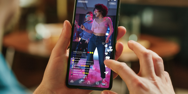 Hands holding a phone displaying a social media dance video