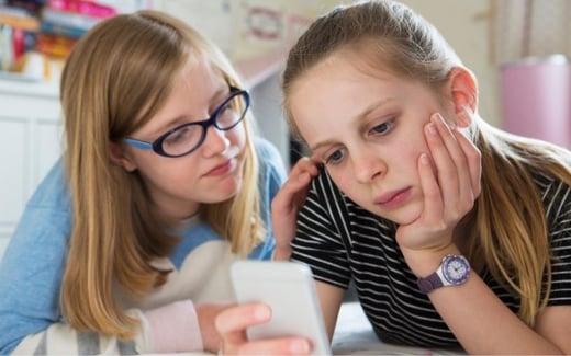 A child comforting another child looking at a phone