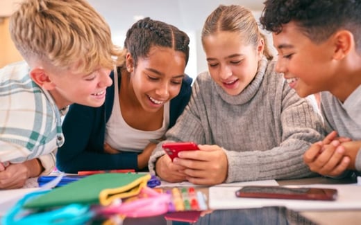 Four young students smiling at a phone