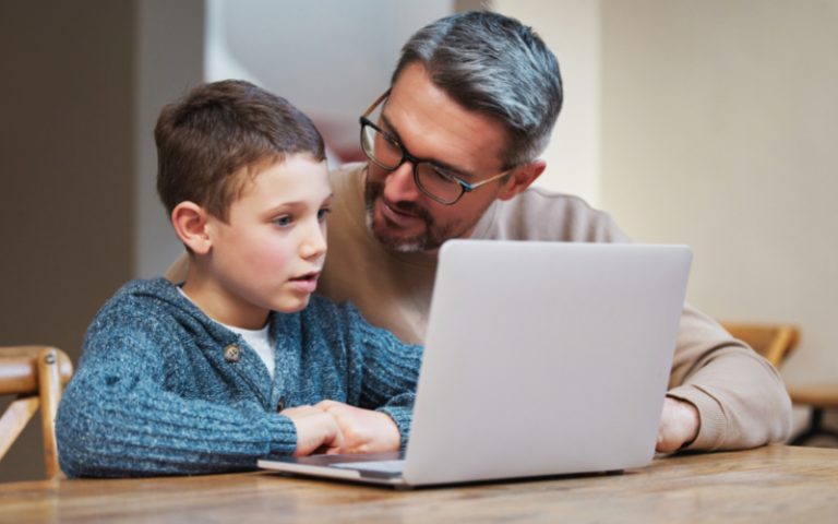 adult helping a child at a laptop