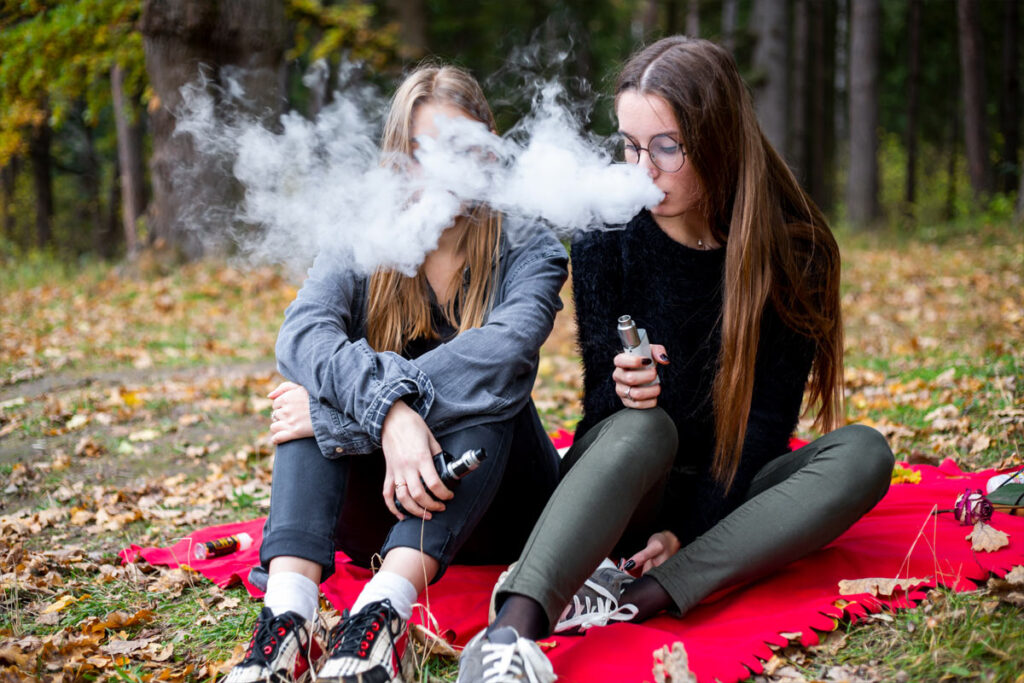two young people vaping near woods