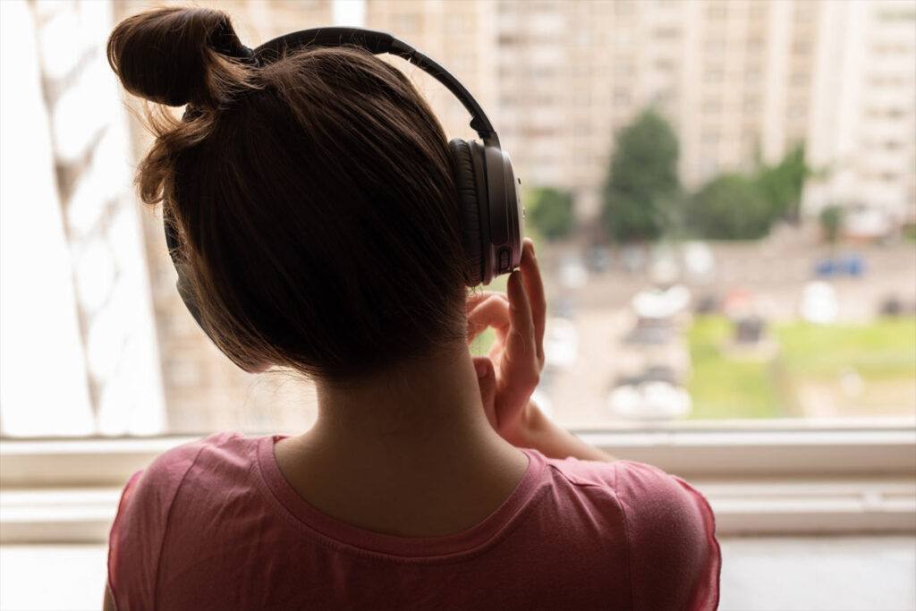 young person at window listening on headphones