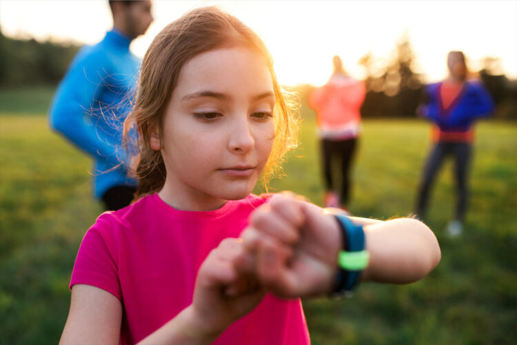 young person checking wrist device during outdoor fitness