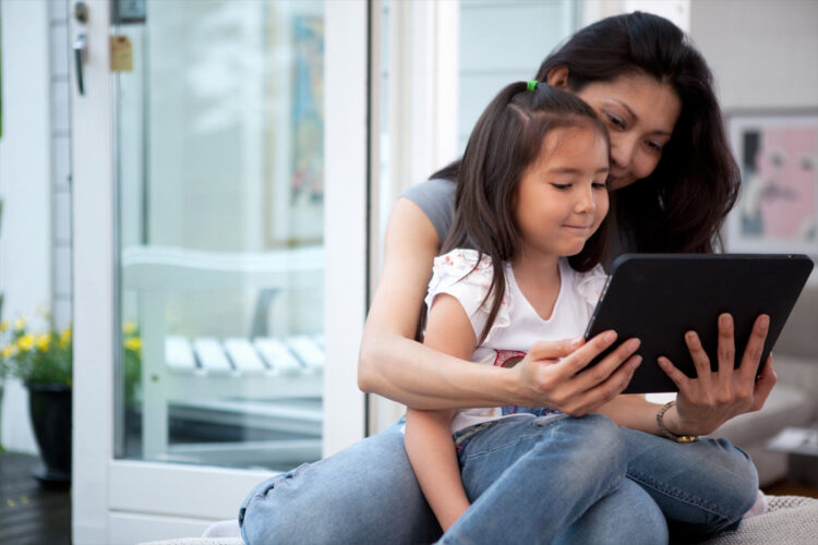 adult with child in lap looking at tablet