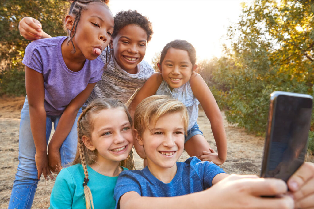 five children taking group selfie outside