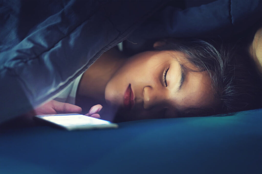 child asleep next to bright phone screen