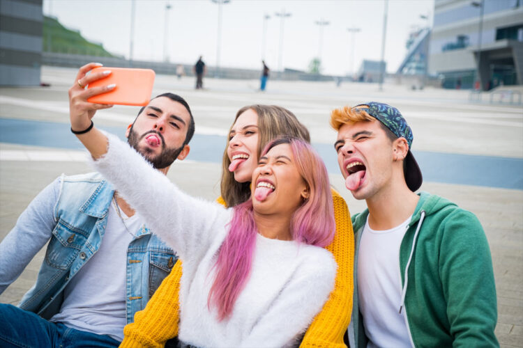 four young adults taking group selfie with tongues out
