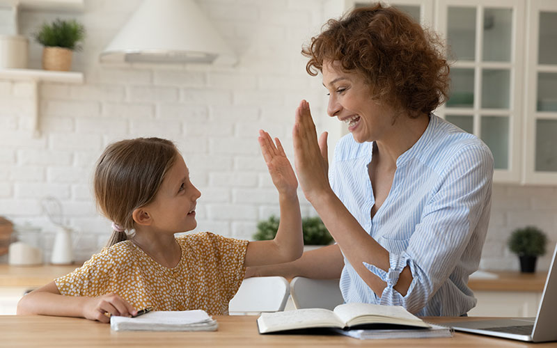 Child and parent high five while working with a book