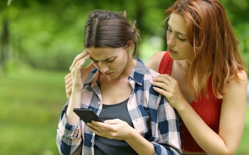 Friend comforts young adult upset at phone