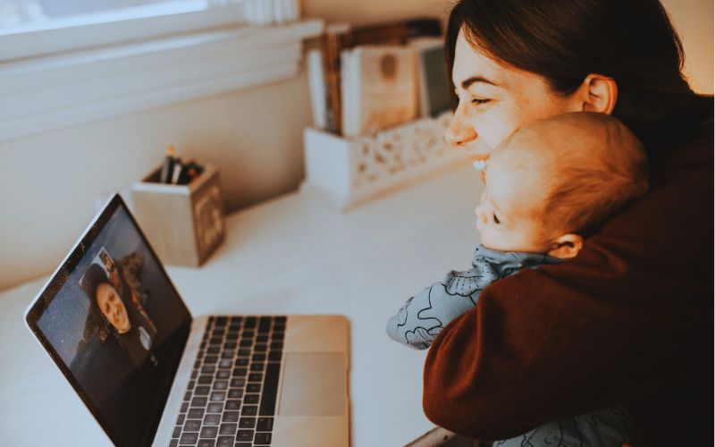 A parent with a baby smiling while on a video call