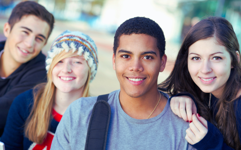 Several young adults smile for the camera outside
