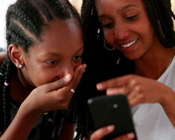 a young person laughs being shown a phone