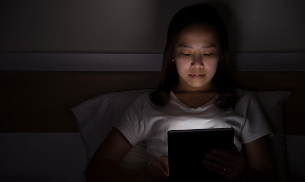 young woman on tablet late at night in bed