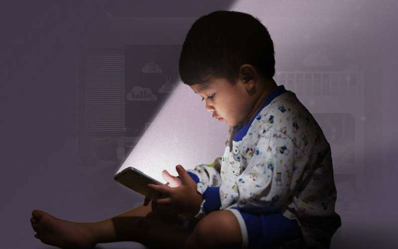 a small child lit by a smartphone