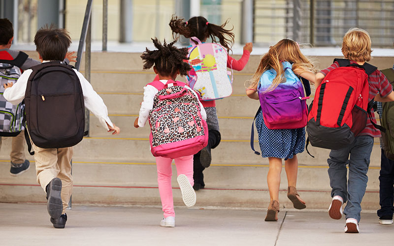 small kids running to class with big backpacks