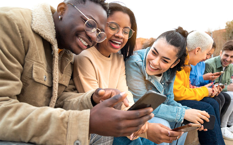 Young people laughing together outside with their phones