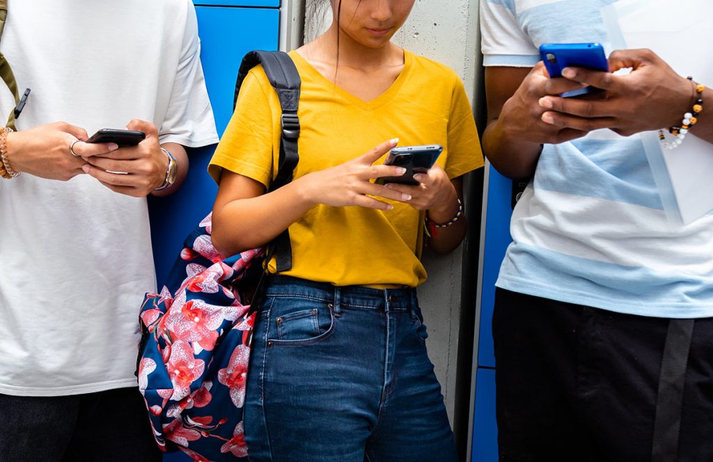 a trio of students using their phones