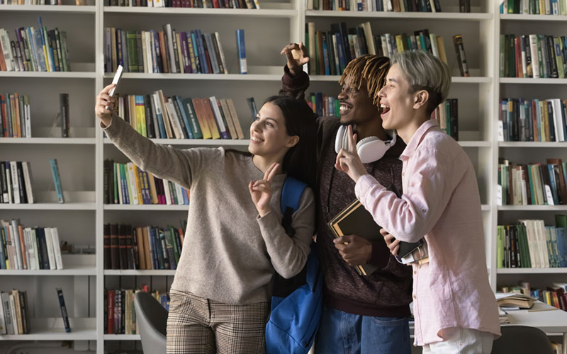 A trio of young people take a selfie in a library
